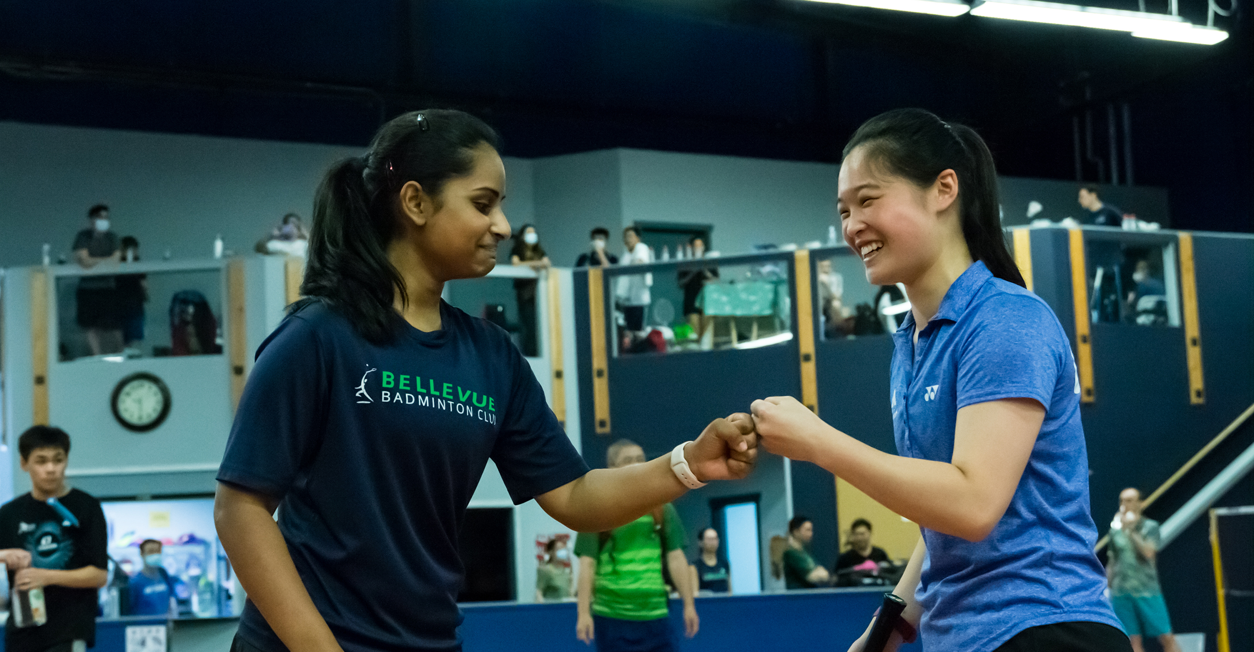 Two badminton players fist-bumping after a game at Bellevue Badminton Club
